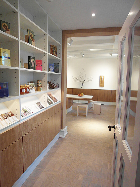 Der Blick in einen Eingangsbereich, der in hellem Holz und mit Ablageflächen für Bücher und Prospekte an einer Wand gestaltet ist.