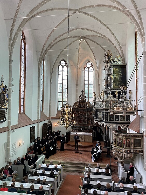 Blick von oben auf einen Festgottesdienst mit vollbesetzten Kirchenbänken in der Klosterkirche Lüne.