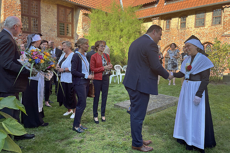 Im Innenhof des Klosters Isenhagen gratuliert eine Reihe von Gästen Cornelia Renders als neue Äbtissin.