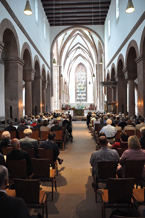 Blick in den Innenraum einer Kirche mit von Besuchern gefüllten Bänken.