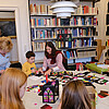Um einen großen runden Tisch in der Bibliothek der Klosterkammer haben sich zwei Frauen und einige Kinder versammelt, die gemeinsam aus buntem Papier Laternen basteln.