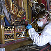 Eine Restauratorin der Klosterkammer in einem Schutzanzug und mit Atemmaske arbeitet an einem Detail des Altars.