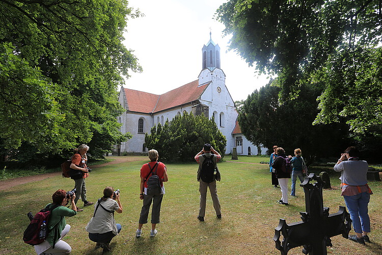 Eine Gruppe von Personen fotografiert das Kloster Marienwerder mit seiner Kirche.