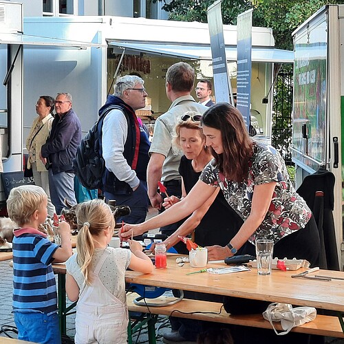 Kinder und Erwachsene stehen an einem Stand im Hof der Klosterkammer